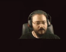 a man with glasses and headphones is sitting in front of a yellow car