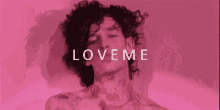 a man with curly hair is singing in front of a pink background with the words `` love me '' .