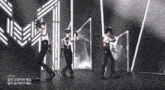 a group of police officers are dancing on a stage with korean writing on the bottom right