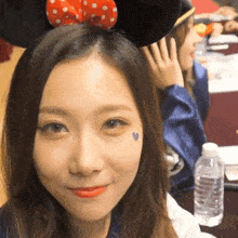 a woman wearing a minnie mouse headband has a small heart on her face