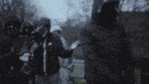 a group of people wearing hooded jackets and masks are standing under trees