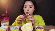 a woman in a yellow sweater is eating ice cream and drinking orange juice