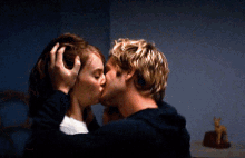 a man and a woman are kissing in front of a statue of a cat