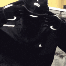 a man wearing a nike hat and gloves is taking a selfie with his phone .