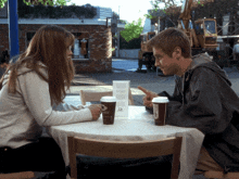 a man and a woman sit at a table with cups of coffee and a sign that says ' a ' on it