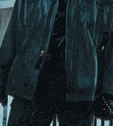 a close up of a man wearing a jacket with a black shirt underneath