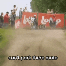 a man on a motorcycle is going down a dirt road with a sign that says lotto on it