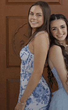 a woman in a blue and white dress smiles next to another woman in a blue and white dress