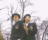 two men wearing suits and hats with the letter b on them
