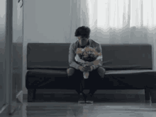 a man is sitting on a couch holding a teddy bear