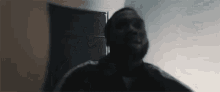 a man with a beard is standing in a dark room looking up .