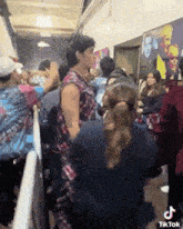 a man in a tie dye shirt is standing in the middle of a crowd of people .