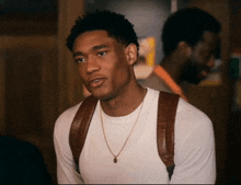 a man wearing a white t-shirt and a brown backpack