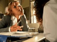 a woman is sitting at a desk with a book on it