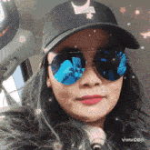 a woman wearing sunglasses and a hat with a crescent moon on the back