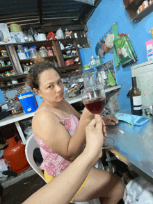 a woman sitting at a table with a glass of wine and a bottle of coca cola