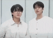 two young men are standing next to each other wearing white shirts and jackets