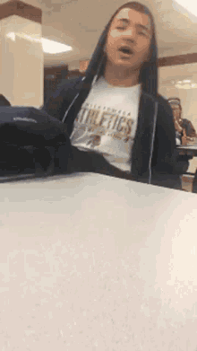a man wearing a hoodie and a shirt that says athletics
