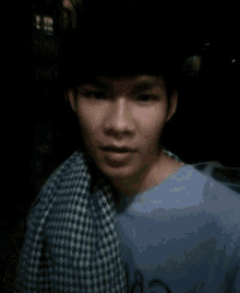 a young man with a scarf around his neck is wearing a purple shirt with the letter r on it