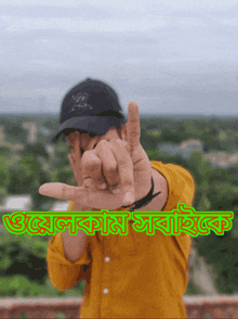 a man wearing a hat and a yellow shirt is making a peace sign with his fingers