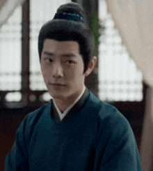 a man with a bun in his hair is wearing a blue shirt