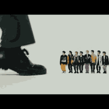 a group of young men are standing next to each other in a line while a person 's foot is standing in front of them