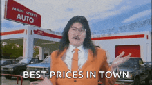 a man in an orange suit and tie is standing in front of a main street auto store
