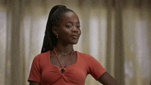 a woman wearing a red top and a necklace looks to the side