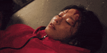 a woman in a red jacket is laying on the floor with blood on her face