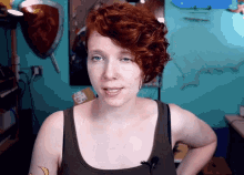 a woman with red hair is standing in front of a blue wall with a shield on it