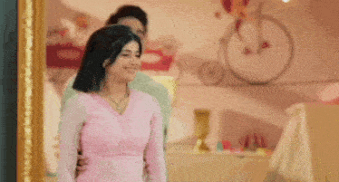 a man and a woman are standing next to each other in front of a mirror .
