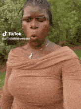 a woman is wearing glasses and a necklace and has a tiktok account