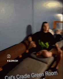 a man is sitting on a couch in a cat 's cradle green room ..