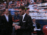 a man in a suit and tie holds a cup in his hand