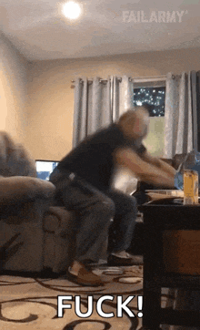 a man is sitting on a couch in a living room with the words fuck written in the corner