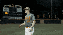 a baseball player with the number 26 on his jersey stands in front of a scoreboard