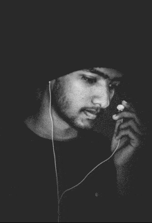 a man wearing ear buds and a beanie looks down at something