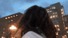 a woman with long hair stands in front of a building at night