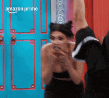 a woman in a black dress is standing in front of a blue door .