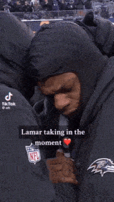 a man wearing a hooded jacket with the nfl logo on the back