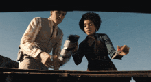 a man and a woman are standing next to each other and looking at something
