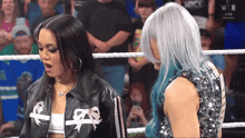 two women are standing in a wrestling ring and one of them has a jacket with the letter n on it
