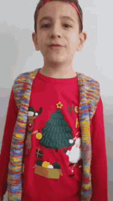a young boy wearing a red christmas shirt with santa claus and a christmas tree on it