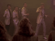 a group of men in suits and ties are dancing in front of microphones
