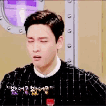 a man wearing a black sweater is making a funny face .
