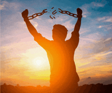 a silhouette of a man holding a broken chain