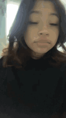 a young girl with her eyes closed is wearing a black sweater