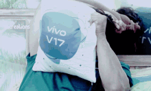 a person laying on a bed holding a pillow that says vivo v17