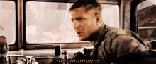 a man is sitting in the driver 's seat of a car and talking to another man .
