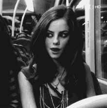 a woman is sitting on a bus with a necklace around her neck .